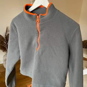 En fin croppad tröja från ASOS i stolen S 🩶 Grå färg med orange dragkedja 🧡