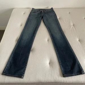 Levis 524 - Vintage Levis 524 jeans. Storlek w28 l36. Låg midja och lätt utsvängda ben, typiska 2000-talsjeans. ”Vaxad” yta. Midjemåttet rakt över är 37-38 cm cm och innerbensmåttet är ungefär 89 cm. Gylfen åker ner men jag har löst det men en liten ring, bild 5