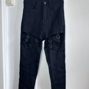 Svarta Jeans - Svarta jeans i storlek XS från Shein. Öppning fram vid låren med metallspännen.  Köpta begagnade, har aldrig använt dom själv. 