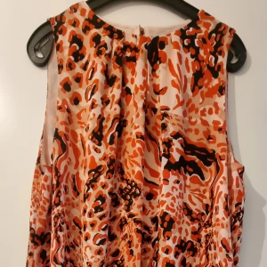 Oanvänd festlig klänning, H&M, 48 - Aldrig använd, dock är prislappen borta. Rak i modellen, knäpps med guldfärgad knapp i nacken. Har en underklänning.  Mått:  Armhåla-armhåla 55cm Axel-nederkant 96cm