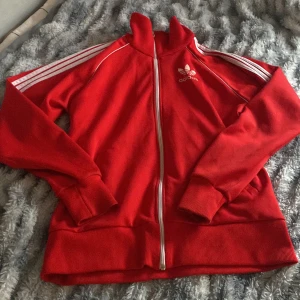 Röd adidas kofta - Skitsnygg kofta men kommer inte till användning, den har lite defekter alltså nån liten fläck(fråga mig i dm om ni undrar eller vill se hur den ser ut på m.m) annars jättebra!! 