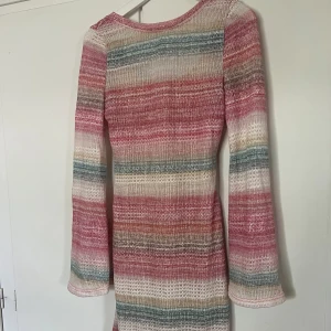 Randig färgglad klänning  - En randig färgglad klänning som är lite ”virkad”.  Med en underklänning i. Djup i ryggen.  Aldrig använd! 