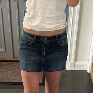 Mörkblå lågmidjad jeanskjol  - Blå lågmidjad jeanskjol från Blue Motion i storlek 38 som jag har gjort om från en längre kjol. Fint skick. Tvärs över midjan är det ca 38 cm + stretch och längs med sidan är det 31 cm. Använd gärna köp nu!