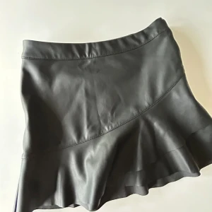 En svart volangkjol med små fina detaljer - En svart volangkjol men fina detaljer på! Bara andvänd ett fåtal gånger! (Bra skick) PRIS KAN DISKUTERAS 