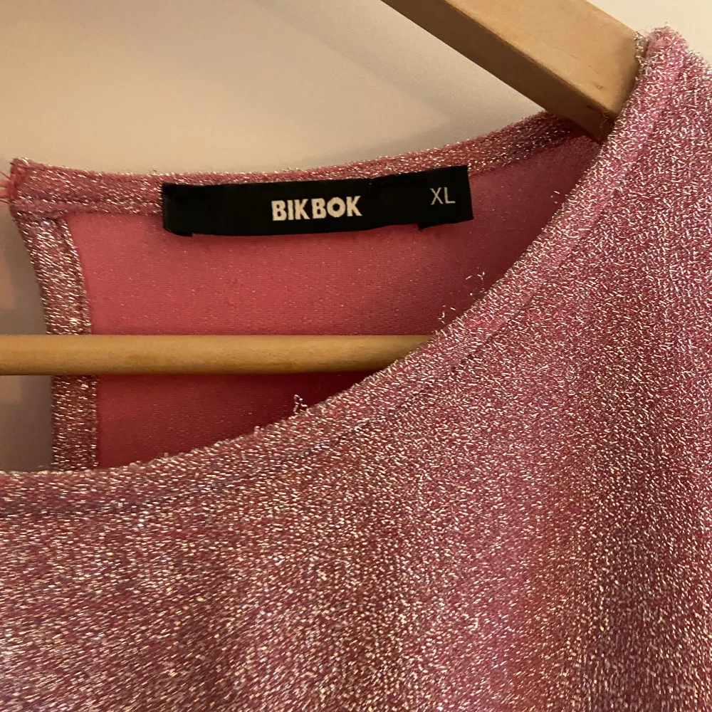 Väldigt söt klänning i rosa glitter med öppen rygg, nästan aldrig använd! Storlek XL men sitter som en L från BikBok . Klänningar.