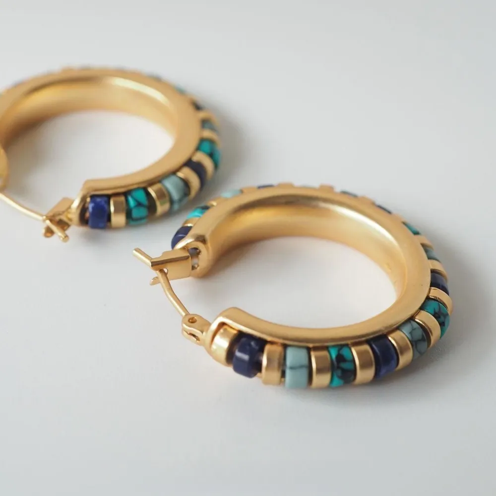 Enhance your bohemian style with these stunning gold hoop earrings, featuring beautiful turquoise and lapis lazuli accents. The unique combination of vib. Accessoarer.