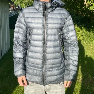 C.P. Company D. D. Shell Hooded Zipped Down Jacket - Köpt från Farfetch och kvitto finns. Jackan var med i en cyckel olycka och har därför många skador. Finns fler så fråga om bilder   Storlek: 46/Small  Nypris 10000kr+ Pris: 899kr