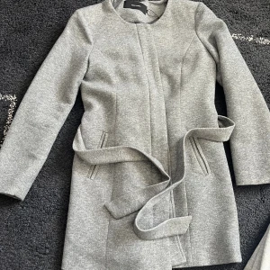 Grå kappa - Grå kappa från Vero Moda i strl L. Använd några få ggr. Säljs för den inte passar längre.