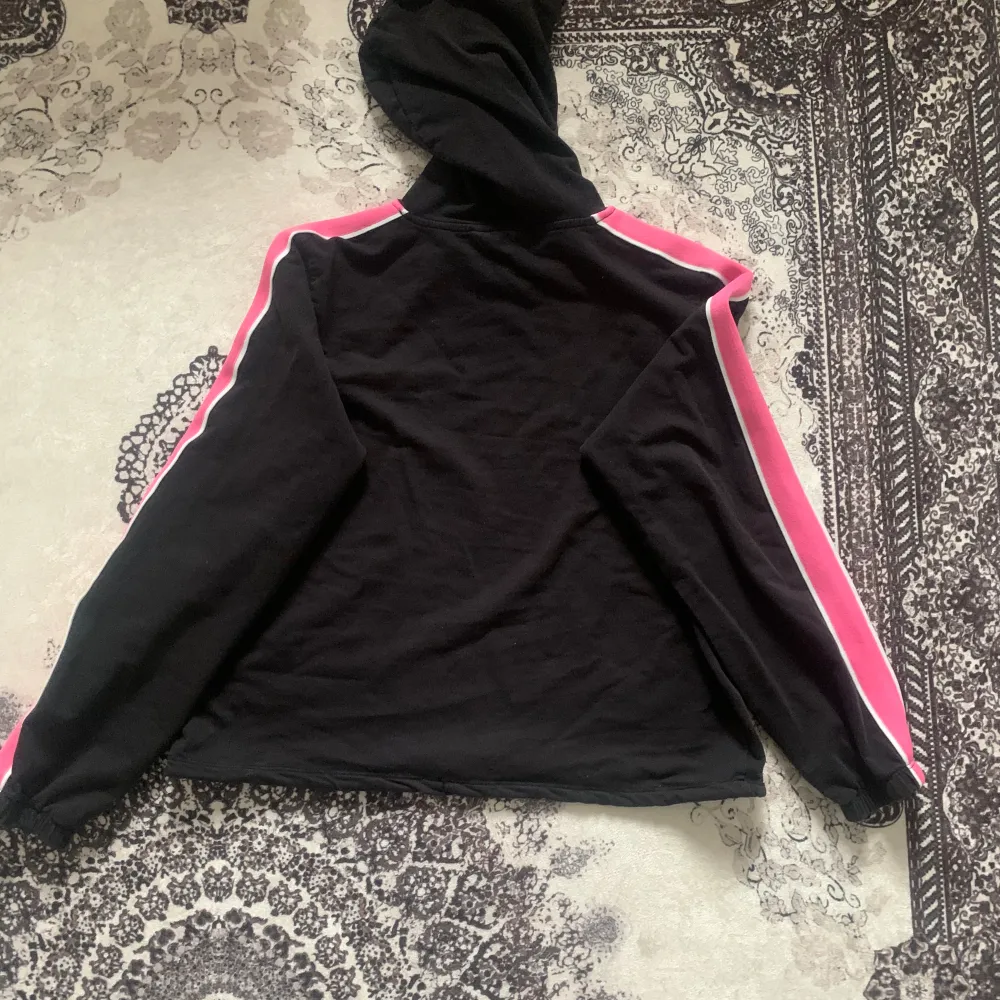 Säljer en svart tröja med rosa sträck på sidan, med luva. Köpt på H&M för 200 kr, säljs nu för 100 kr eller enligt överenskommelse. Använd en gång och tvättad. Perfekt för en avslappnad och trendig look! ❤️. Tröjor & Koftor.