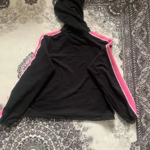 Säljer en svart tröja med rosa sträck på sidan, med luva. Köpt på H&M för 200 kr, säljs nu för 100 kr eller enligt överenskommelse. Använd en gång och tvättad. Perfekt för en avslappnad och trendig look! ❤️