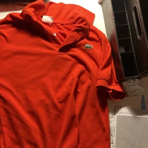 Lacoste röd piké - Jätte snygg röd lacoste piké använd ett par ggr men ftf i bra kvallité S men passar M
