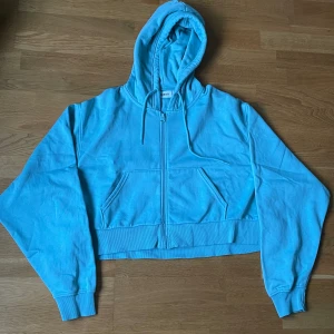 Croppad zip up - En croppad zip up hoodie. Färgen är mer ljus turkos i verkligheten. Bra skick, bara använd fåtal gånger.