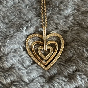 Hjärthalsband - Guldigt halsband (inte riktig guld). Ganska långt. Väldigt lite använt.
