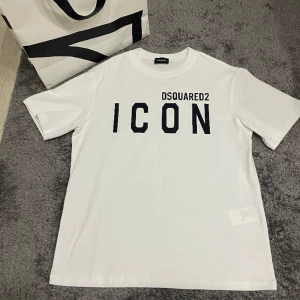 Dsq2 icon t-shirt - Jag vill nu sälja denna ikoniska Dsqaured2 Icon T-shirten som är riktigt snygg och lyxig dessutom perfekt inför våren. Perfekt för att ge din outfit en trendig look! Storlek L men passar en större M med! Vid minsta fundering hör av er✔️