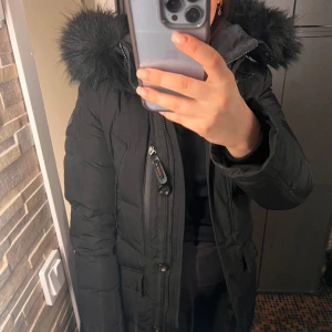 Hollies Wilma vinterjacka  - Hollies vinterjacka i modellen Wilma. Svart avtagbar fuskpäls. Jackan är i jätte fint skick då den knappt är använd, men har ett litet hål i en liten ficka. Storlek 38, nypris 3799:- 