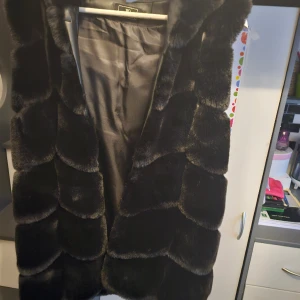 Päls väst,  ny skick  - Storlek s/m. Svart, luva, ny skick