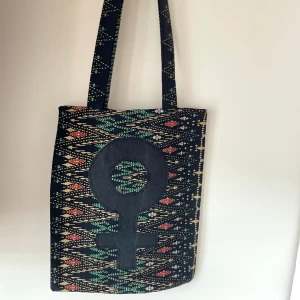 Tygkasse, tygväska, tygpåse - Handsydd tygkasse med motivet ”feminist”.   Tillverkad i 100% återvunna textilier.   Mått: 32x35 cm  Hämtas på Södermalm alternativt skickas med post. 