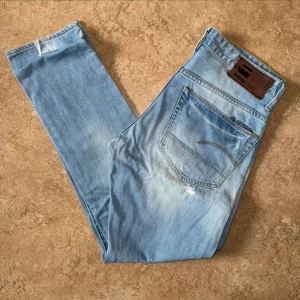 G-Star Raw 3301 Tapered Blåa Jeans - G-Star Raw jeans i modellen 3301 Tapered, använda men i gott skick. Storlek: 34 W, 32 L, Midja: 44.5 cm Ytterben: 106.5 cm Benöppning: 17 cm