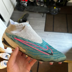 Nike Phantom GX Elite DF AG-PRO Blast - Blå/Rosa/Vit/Blå - Fotbollsskor från förra säsongen som jag vill sälja. Köpta från unisport för 3249kr Skick 8/10 Fråga om osäker med storlek eller annat!