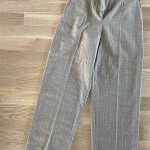 Sandro Paris kostymbyxor - Beige kritstrecksrandiga kostymbyxor från Sandro Paris i storlek 36. Otrolig kvalité. Nästintill oanvända.   Jag är 1,60 cm, mäter 95 cm runt stuss och 70 cm i midja.   Nypris 2400 kr. 