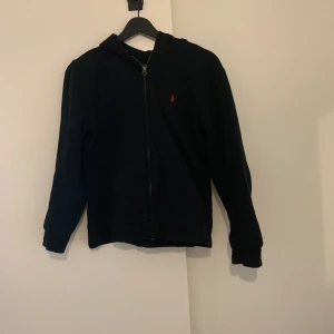Polo Ralph Lauren  - Polo zip up, röd och svart, storlek 160. Fint skick inga defekter, har haft den nu i dryga 4 månader och den har blivit för liten.  Fint skick inga defekter  Färg: svart och lite rött Storlek 160 