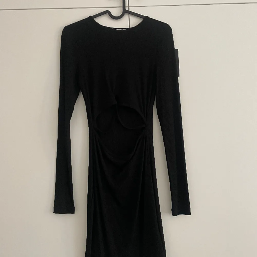 Säljer denna svarta klänning med lite detaljer på magen i storlek XS. Aldrig använd så prislappen är kvar . Klänningar.