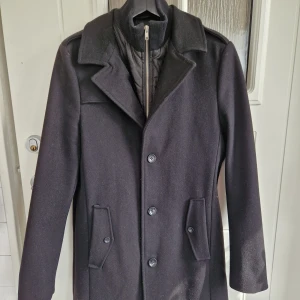 Ullkappa herr - Använd fåtal gånger. Hål i ena fickan som lätt kan sys ihop, annars jättefint skick!  Innerdelen kan enkelt tas bort med dragkedja. 