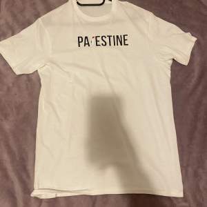 Vit t-shirt med text som säger ” PALESTINA”