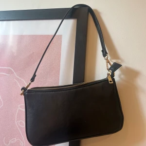 Svart väska  - Svart väska med guldiga detaljer. Använd men i bra skick.