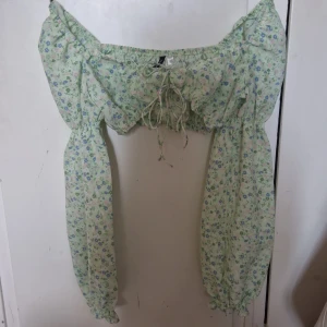 En fin ljusgrön sommar topp med blommor på. - En fin ljusgrön sommar topp med blommor på och aldrig använd. Väldigt fin med tunt material. Den är töjbar och men kan välja om man vill ha axlarna uppe eller nere. 