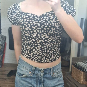Blommig topp - Blommig topp från H&M med dragband framtill som gör det möjligt att justera passformen och längden. 