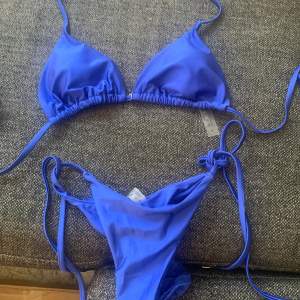 Säljer en superfin blå bikini med knytband. Överdelen har trekantsformade kupor och underdelen har en snygg rynkad detalj på baksidan. Perfekt för sommarens alla bad och strandhäng! 💙