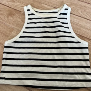 Randig ribbad linnetopp - Säljer en superfin randig linnetopp i ribbat material. Toppen är ärmlös och har en croppad passform, perfekt för sommaren! Den är vit med svarta ränder och är både bekväm och stilren. Passar perfekt till både jeans och kjol. Köp direkt eller ge prisförslag💛