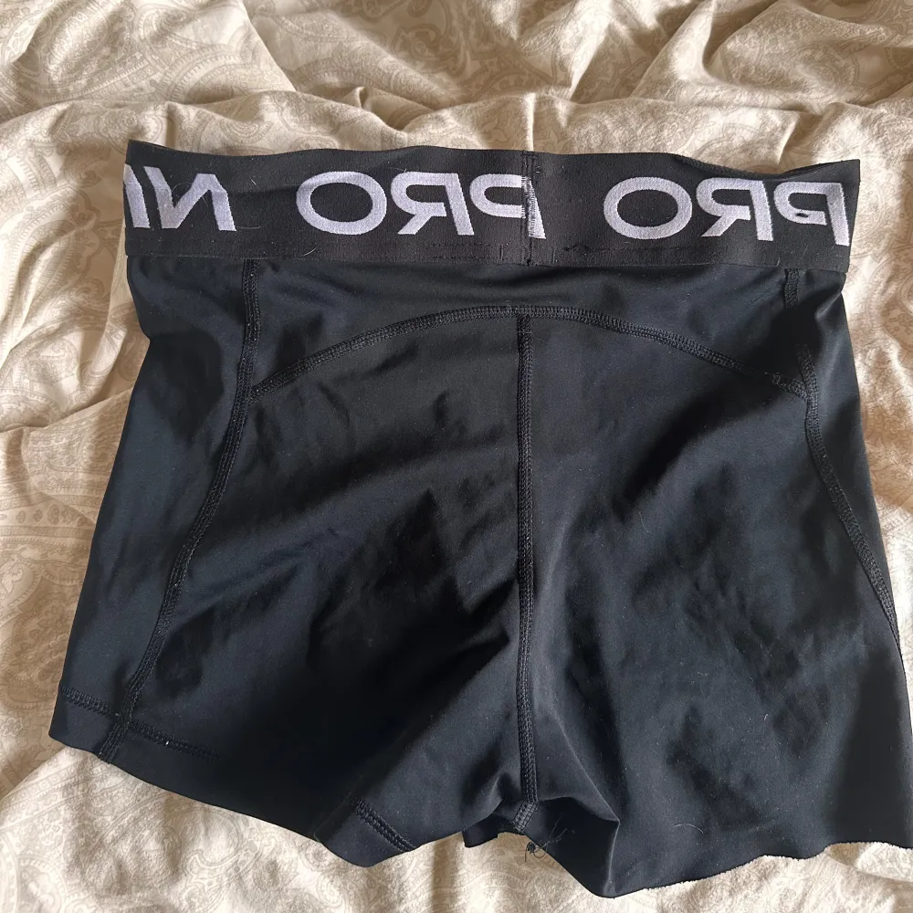 Säljer ett par svarta träningsshorts från Nike Pro. De är använda några gånger och har en tight passform. Shortsen är gjorda av polyester och har en elastisk midja med Nike Pro-loggan. Perfekta för träning eller andra sportaktiviteter.. Shorts.