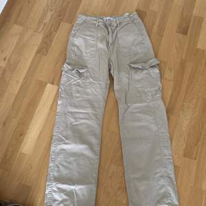 Ett par beige cargobyxor från Zara i storlek EUR 36. Byxorna har flera fickor och är tillverkade i Bangladesh.