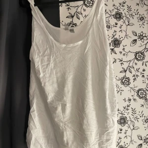 Vit linnetopp - Säljer en enkel och stilren vit linnetopp. Perfekt för varma sommardagar eller som ett basplagg i garderoben. Toppen är ärmlös och har en lös passform, vilket gör den superbekväm att bära. Materialet känns mjukt och skönt mot huden.