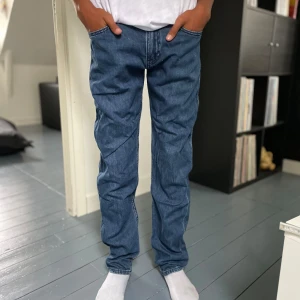 Blå jeans med fickor - Säljer ett par snygga Ck jeans med fickor på sidorna och bak. De är i bra skick och har en normal passform. Perfekta för vardagsbruk och kan matchas med nästan vad som helst. De har en dragkedja och knappar framtill.