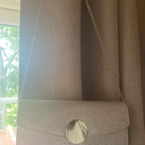 TIAMO Cheryl Väska Glitter Silver - Kuvertväska med stort fack och litet, öppet på insidan. Locket stängs med magnetlås, silverfärgad kedja som axelrem Använd under en kväll. nyskick. Ej märke alls. Väldigt fin.  bra storlek rymde mkt. Ta chansen hitta en fin väska till bal💛 nypris 399