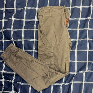 Cargo byxor (JACK&JONES - Bruna cargo buxor från JACK&JONES med benfickor, storlek W32 L34, nypris runt 500 kr. 