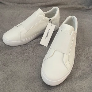 Calvin Klein sneakers - Helt oanvända vita sneakers med lappen kvar💕Säljer pga av att de ej kommit till användning🤍 Nypris 1 395:- 