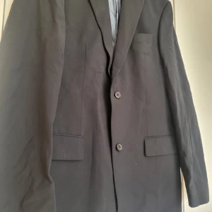 Kavaj/Blazer Hugo Boss  - Kavaj/Blazer av märket Hugo Boss  På bilden ser den brun ut, det är på grund av solljuset i min lägenhet. Kavajen är svart!  Herr 