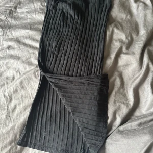 Svart ribbad kjol - En svart ribbad kjol med en tight passform. Kjolen är av medellängd och har en elastisk midja för extra komfort.