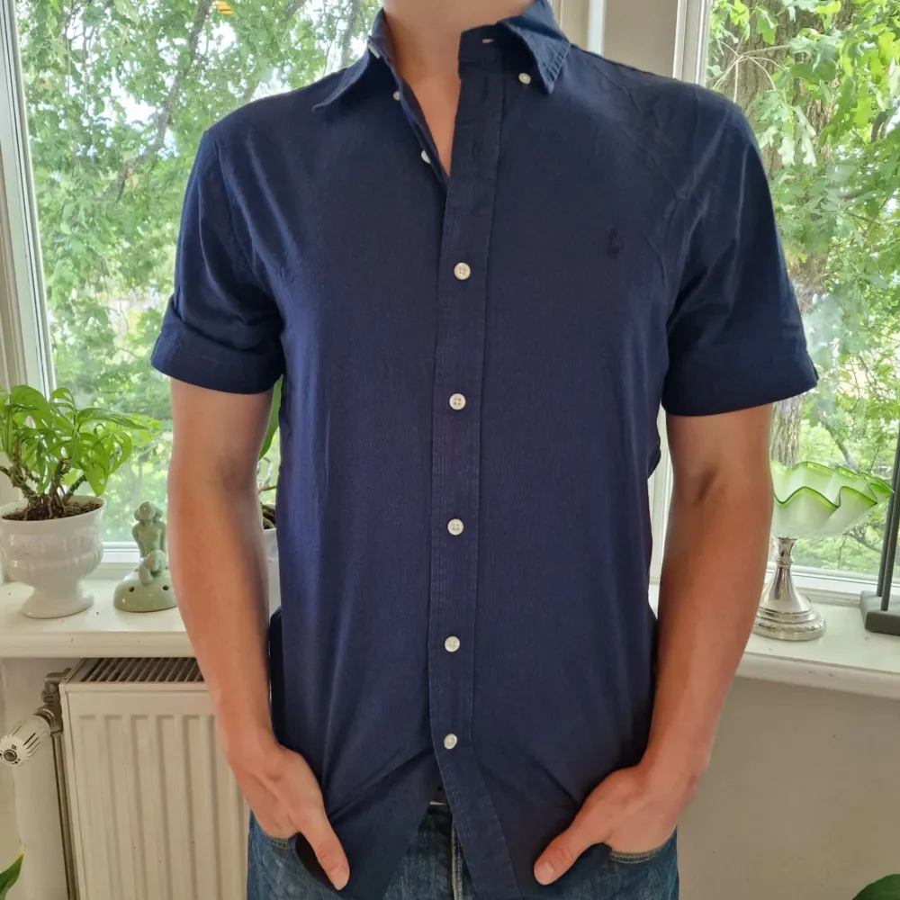 Marinblå kortärmad Ralph Lauren skjorta. Slim fit passform. Modellen på bilden är 175cm lång och brukar ha på sig S/M.  Frågor och funderingar är välkomna!  Mer på profilen ❗️O5 276. Skjortor.