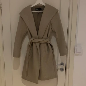 Kappa zara - Kall beige kappa från zara i storlek XS, passar S med. Har fickor, rep runt midjan och luva. Fint skick