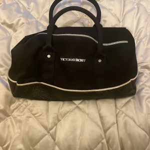 Väska från Victoria’s Secret - Nästan oanvänd i fint skick, i guld, svart och glitter.