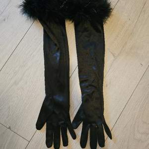 Beskrivning: Svarta aftonhandskar med svart svandun med glitterstrån. Storlek: One size Skick: Mycket gott skick Material:  Nakenkatt finns i hemmet