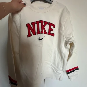 Nike retro sweatshirt XS - En vit Nike tröja i retro stil med röd logga och svarta detaljer på ärmarna. Tröjan är i bra skick och har endast testats.  OBS liten i storleken! Herr strl XS.