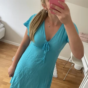 Blå v-ringad klänning - Superfin blå v-ringad klänning med en rosett på framsidan. Den kommer från Primark och är ganska stor i storleken. Aldrig använt☺️💗