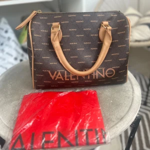 Mario Valentino väska - Använd men väldigt fint skick.  Axelrem och dustbag medföljer.  Har små slitningar på färgen i hörnen, men man märker det knappt.  