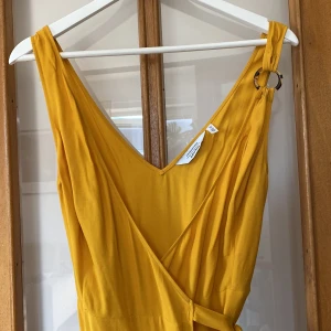 Gul klänning i viskos  - En superfin klänning från otherstories. Använd 1 gång och är därmed i väldigt fint skick. Perfekt till sommarfest eller som bröllopsgäst! 